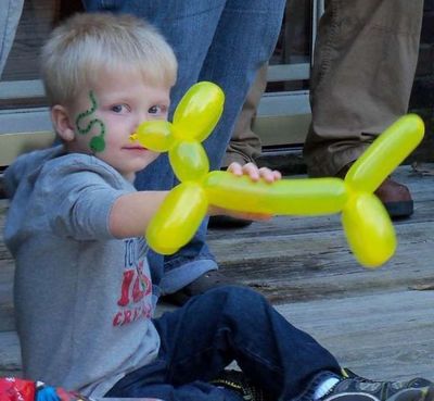 A young child holding a yellow balloon dog